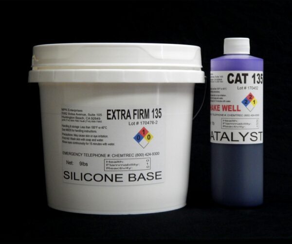 A large white bucket labeled "10 lb Kit : Extra Firm 135 silicone base" next to a purple and white bottle labeled "catalyst," both on a black background.