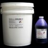 A white plastic bucket labeled "44 lb Kit : Extra Firm 135 – (35 shore A durometer) – Regular Pot Life Mold Making Silicone" and a purple bottle labeled "catalyst" against a black background.