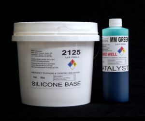 A white plastic bucket labeled "#2125 Base w/ MM Green Catalyst" and a blue cylindrical bottle labeled "10 lb Kit" against a black background.