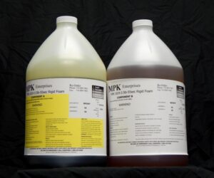 Two large jugs of 16 lb Kit : MPK-1019 : 3.5 lb Rigid Pour Foam, labeled with technical and warning details, against a black backdrop.