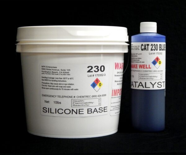 Two chemical containers, a large white tub labeled "QM 230 FG B: 30 shore A Platinum Silicone" and a smaller blue bottle labeled "Blue Catalyst", against a black background.