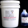 A white bucket labeled "44 lb Kit : QM 230 FG B: 30 shore A – Platinum Silicone" and a blue bottle labeled "Blue Catalyst" on a black background. both containers display hazard warnings and product information.