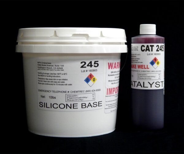 A white plastic bucket labeled "11 lb Kit : QM 245 : 45 shore A – Platinum Silicone" and a smaller purple-gray bottle labeled "catalyst" against a black background.