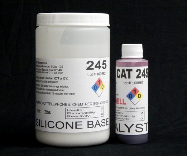 Two containers labeled "2 lb Kit : QM 245 : 45 shore A – Platinum Silicone" and "catalyst," featuring hazard symbols, emergency contact numbers, and storage instructions, set against a black background.