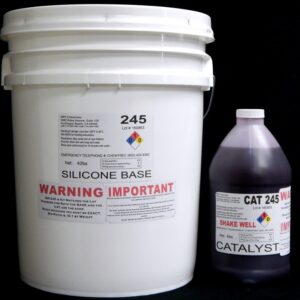 A white plastic bucket labeled "44 lb Kit : Food Grade QM 245 FG R: 45 shore A – Platinum Silicone" next to a dark bottle labeled "Red Catalyst," both against a black background.