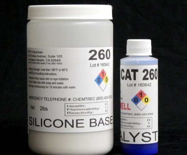 Two bottles labeled "Food Grade QM 260 FG B" and "Platinum Silicone Blue Catalyst" with hazard symbols and technical details, on a black background.