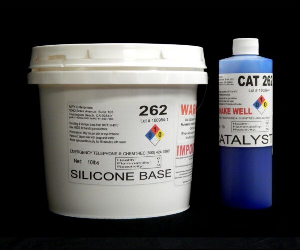 A white plastic bucket labeled "11 lb Kit : QM 262 : 62 shore A – Platinum Silicone" next to a blue and white spray can labeled "catalyst" on a black background.