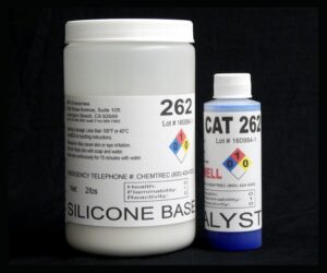 Two bottles labeled "2 lb Kit : QM 262 : 62 shore A – Platinum Silicone" and "catalyst" with hazard identification numbers on a black background.