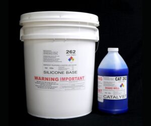 A white bucket labeled "44 lb Kit : QM 262 : 62 shore A – Platinum Silicone" and a blue bottle labeled "catalyst" against a black background.