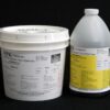 Two industrial containers labeled "1 Gal Kit (11.5 lb) : MPK-301 : 6 lb Medium Pour Foam – (3.5 lb A and 8 lb B) re-order" with chemical content details against a black background. One is a white bucket, and the other a white bottle.