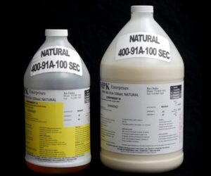 Two large industrial chemical containers, one clear and one red, labeled "1 Gallon Kit MPK 400-91A-100sec NATURAL," against a black background.