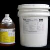 Two industrial containers on a black background, one a labeled jug of 5 Gallon Kit MPK 400-61A-100sec NATURAL degreaser, the other a white plastic bucket with a label.