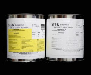 Two labeled 20 lb Kit : MPK-18-80 TOOLING RESIN containers with detailed instructions and warning labels, placed side by side against a black background.