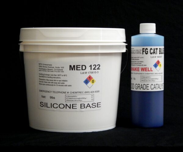 A white bucket labeled "10 lb Kit : Medium 122 FG Cat Blue – (22 shore A durometer) – Food Grade Mold Making Silicone" next to a blue bottle labeled "fg cat blue," both against a black background.