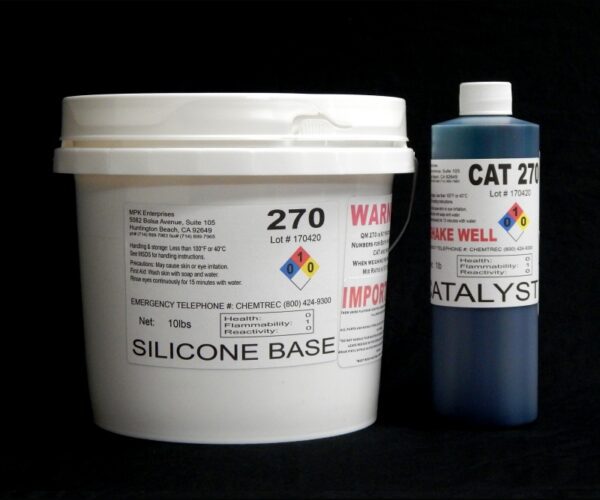 A white bucket labeled "11 lb Kit : QM 270 : 70 shore A – Platinum Silicone" and a blue bottle labeled "catalyst" on a black background, both featuring hazard symbols and product information.