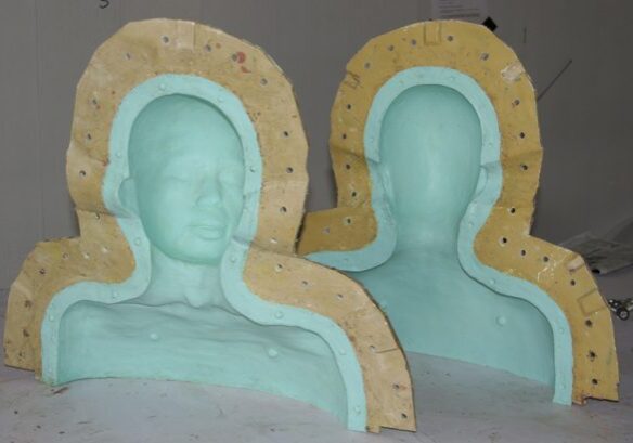 Two foam head molds supported by wooden frames in a workshop setting.